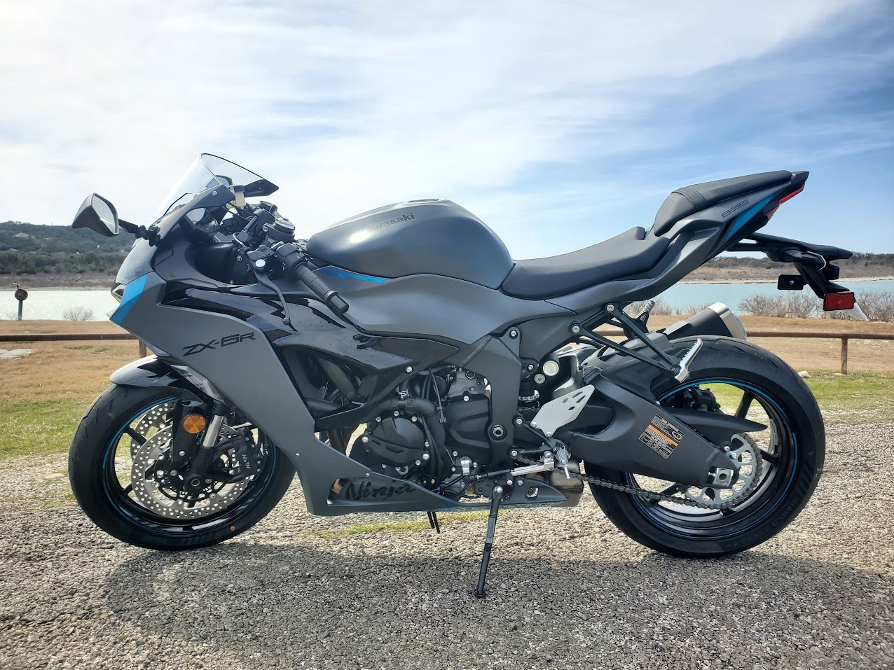 Side profile of the gray Kawasaki Ninja with blue accents beside a lake